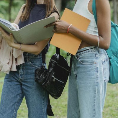 Photo by Zen Chung Crop faceless diverse classmates reading new material in park