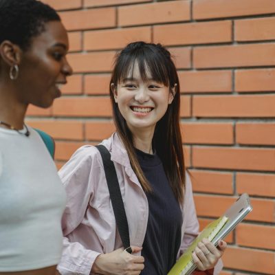 Happy multiethnic students chatting and outside brick building