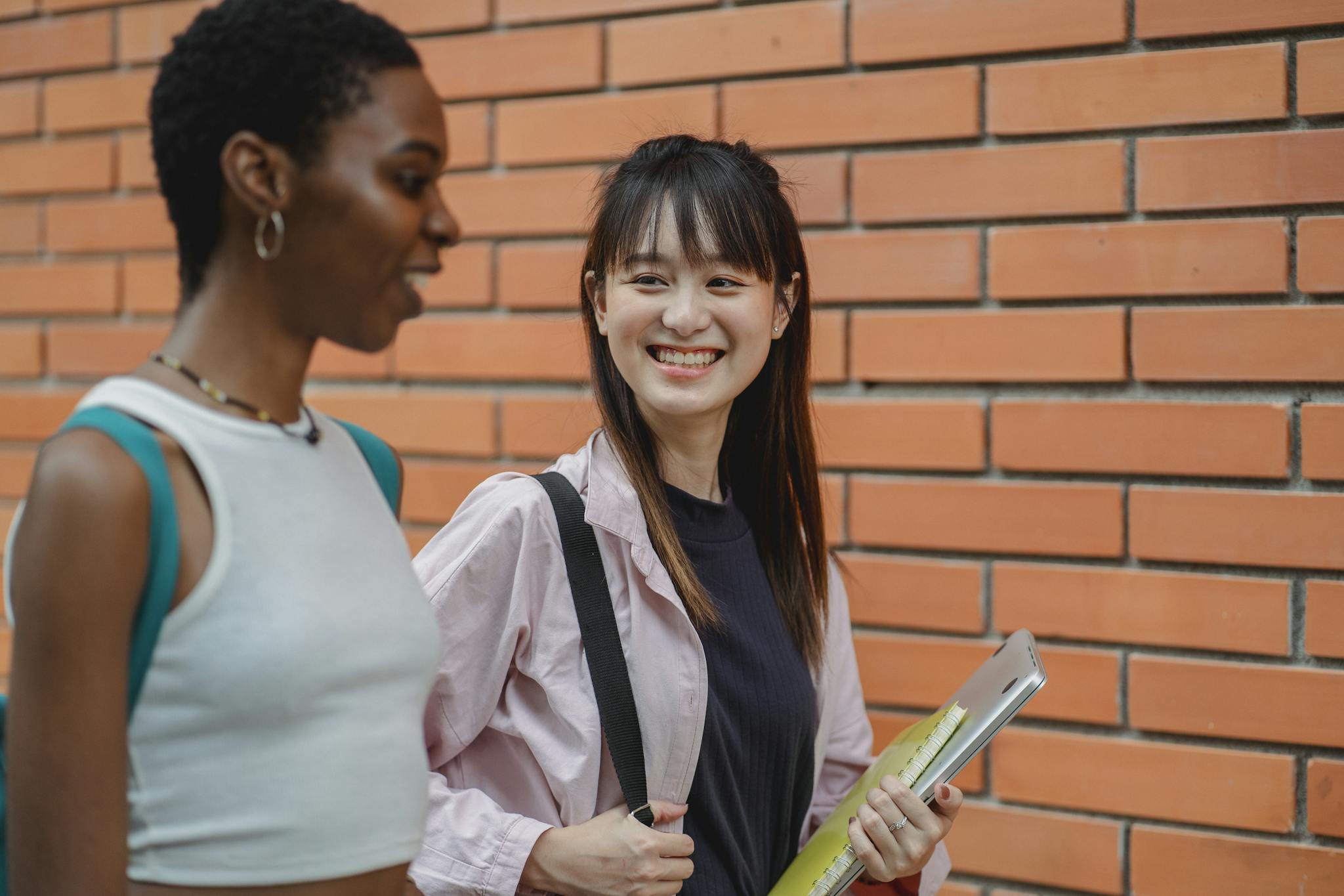 Happy multiethnic students chatting and outside brick building
